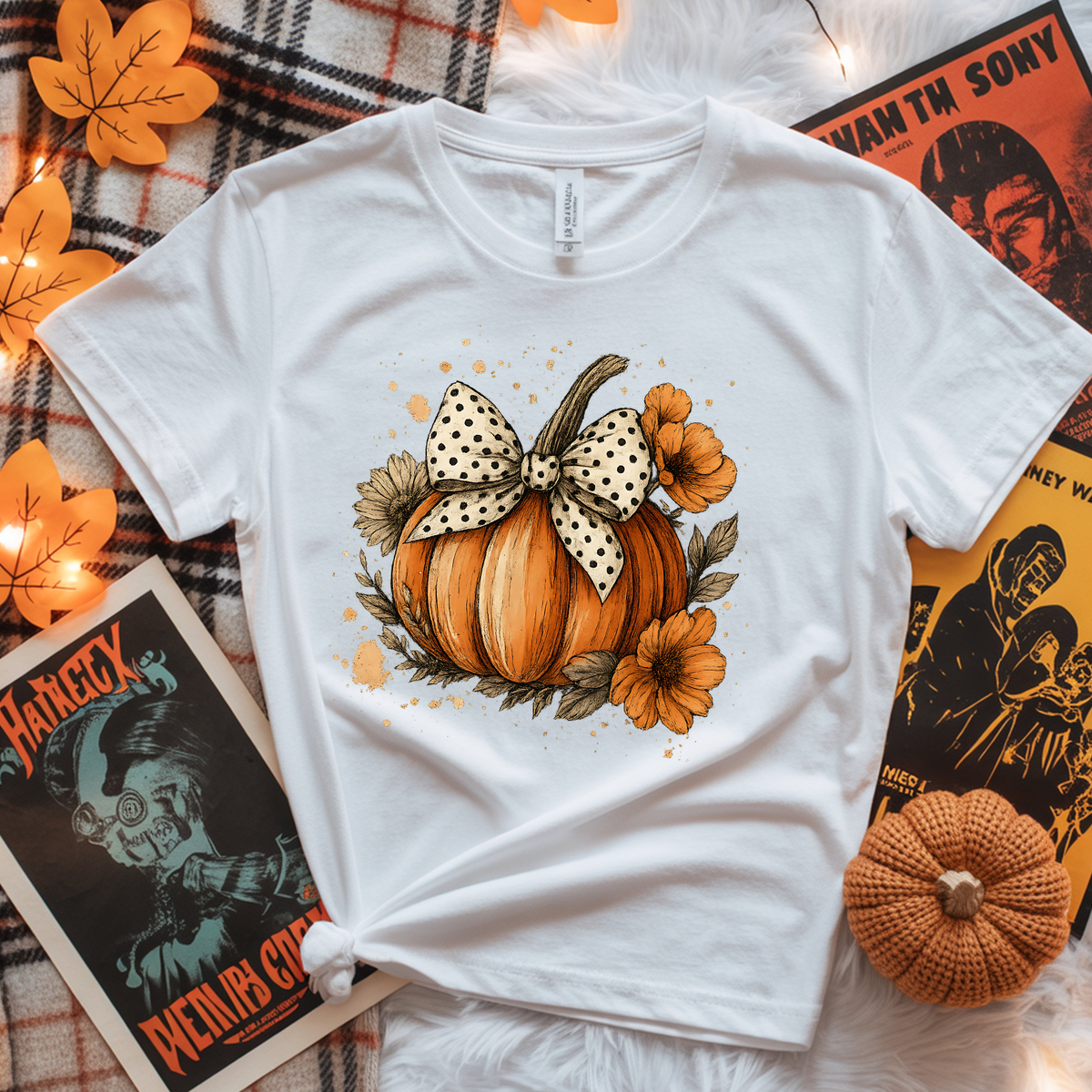 White shirt features a large orange pumpkin with a black-and-white polka dot bow, orange flowers, and fall leaves on the front.