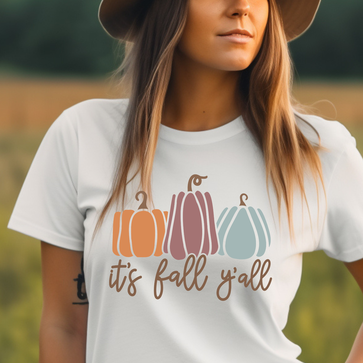 white graphic t-shirt with a fall-themed pumpkin design and the text 'it's fall y'all' in brown script
