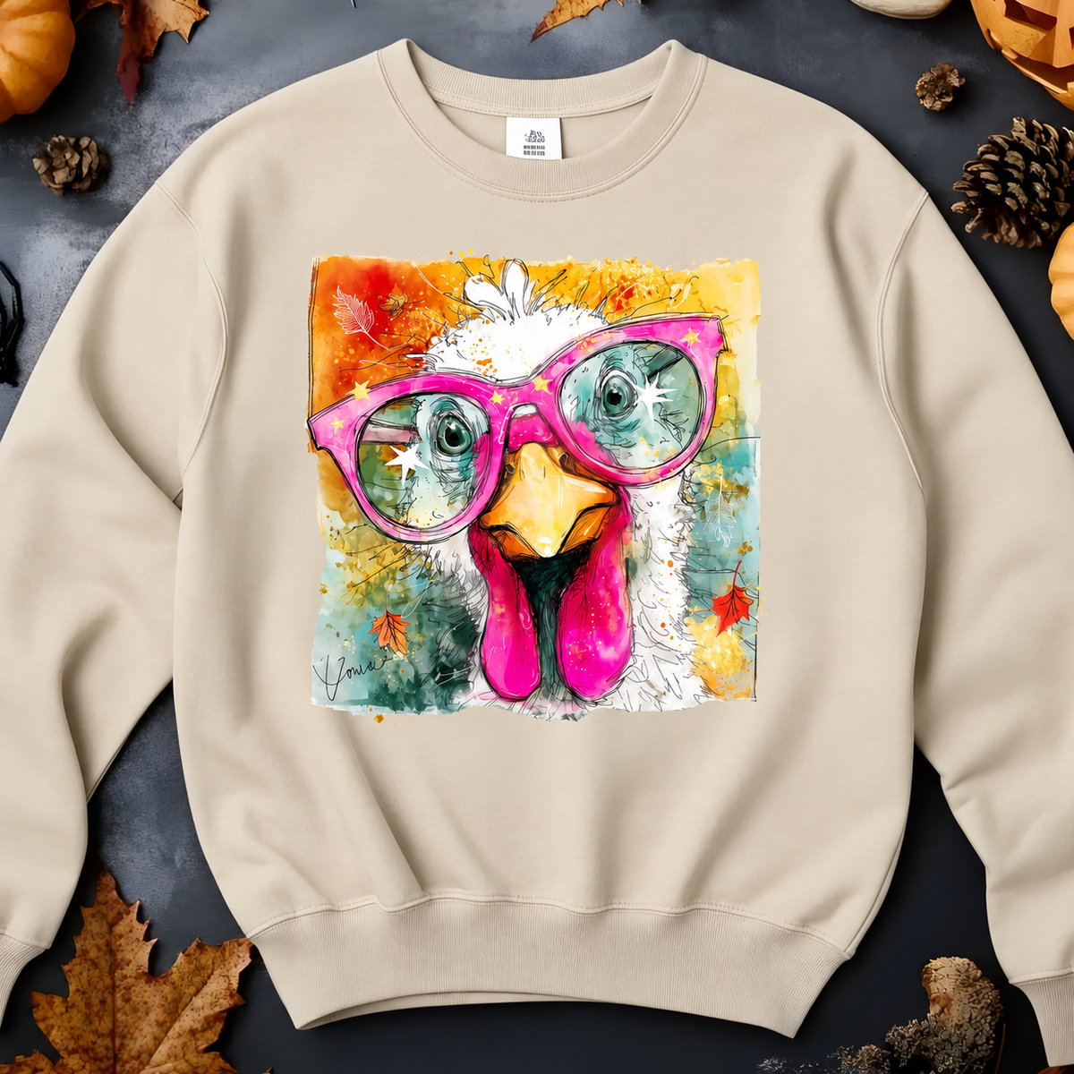 A sand crewneck sweatshirt features a large square graphic print of a white chicken wearing bright pink glasses.
