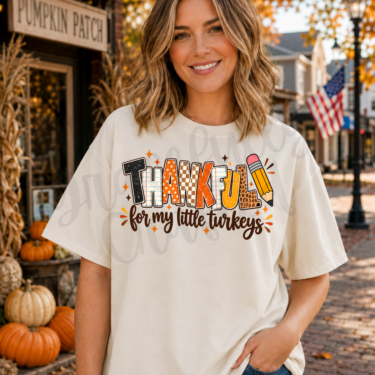 A woman wearing a cream-colored graphic t-shirt with a 'Thankful for my little turkeys' design.