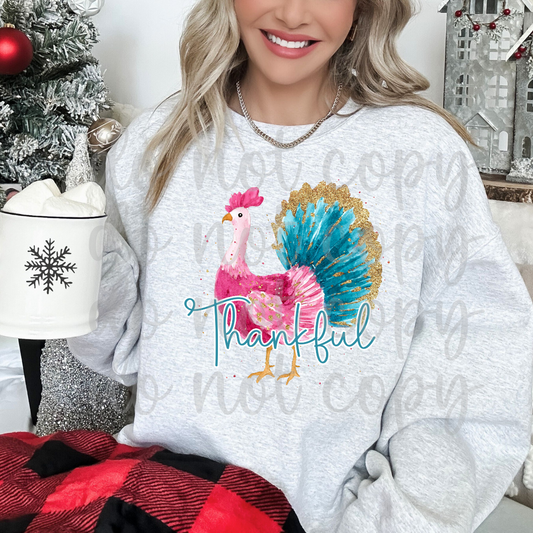 Whimsical watercolor Thanksgiving turkey in bright pink and turquoise with gold glitter-style accents on its feathers and turquoise Thankful script lettering.