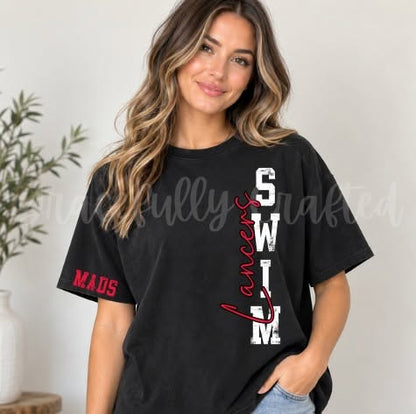 A woman wearing a black graphic t-shirt with 'SWM' in distressed white letters and 'Lancers' in red script, plus 'MADS' in red on the sleeve, set against a neutral indoor background.