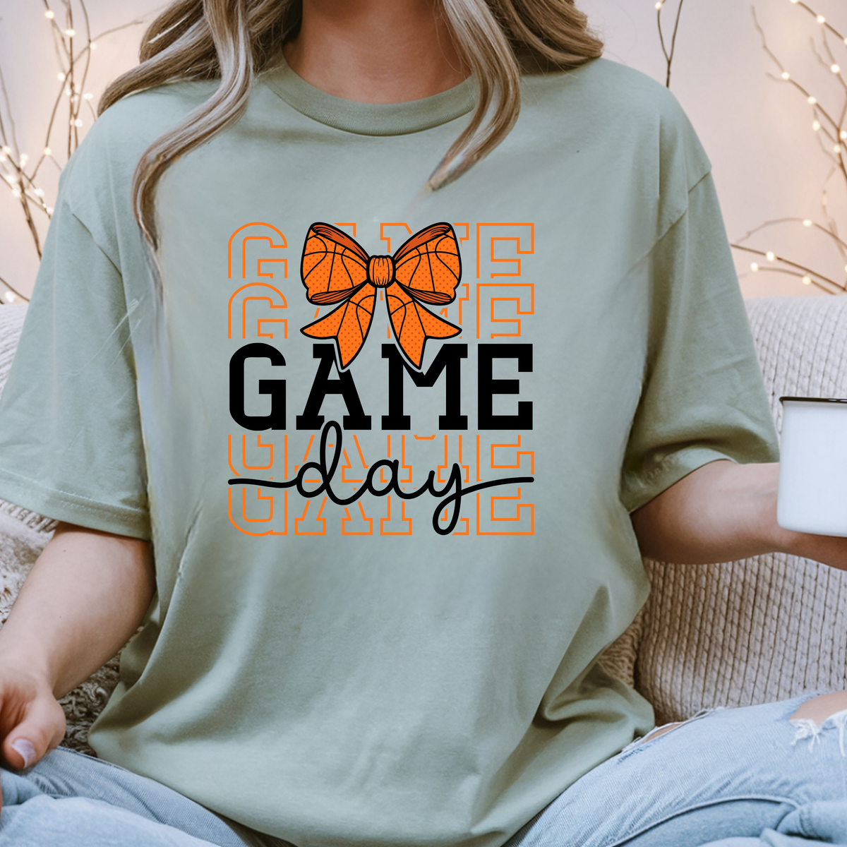 Sage green shirt featuring GAME DAY lettering in orange and black with a decorative basketball bow.
