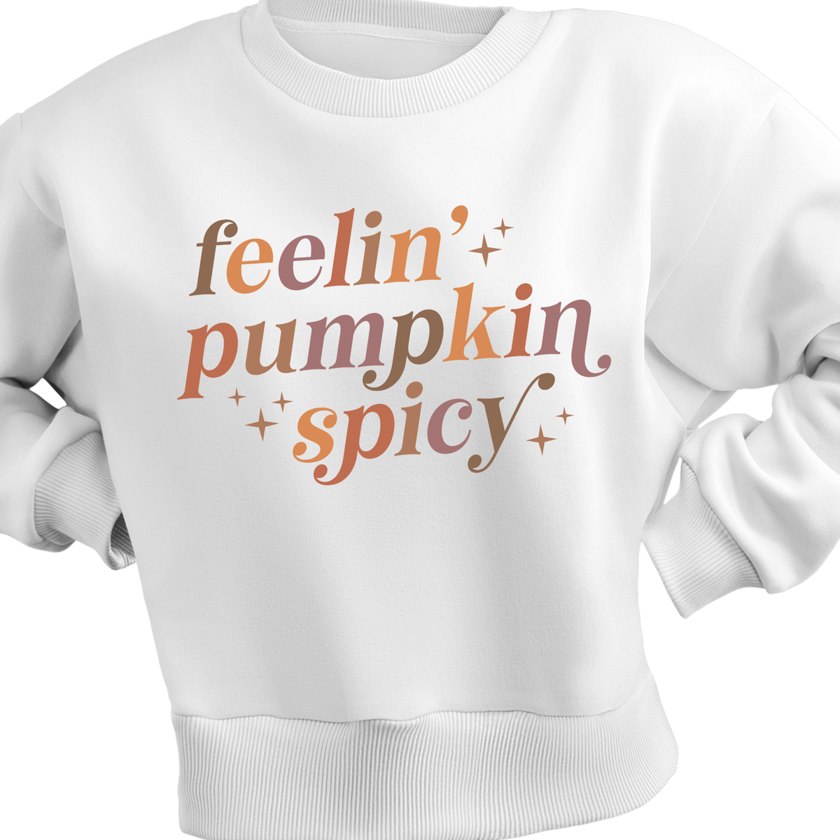 A white crewneck sweatshirt featuring the phrase 'feelin' pumpkin spicy' in a stylized, warm-toned font with small star accents on the front.