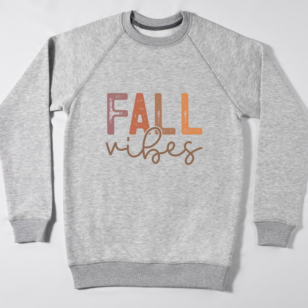 A heather gray crewneck sweatshirt with 'FALL vibes' printed on the chest in a textured, multi-toned autumn font