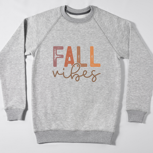 A heather gray crewneck sweatshirt with 'FALL vibes' printed on the chest in a textured, multi-toned autumn font