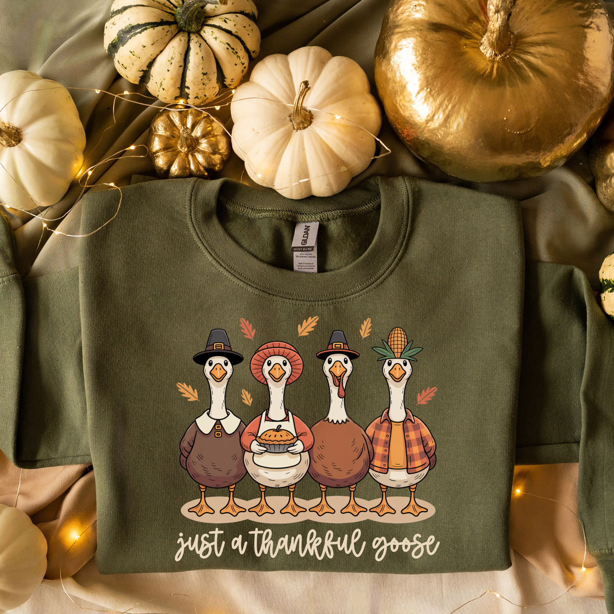 Military green crewneck sweatshirt featuring a graphic of four cartoon turkeys in Pilgrim hats with the text 'just a thankful goose' underneath.