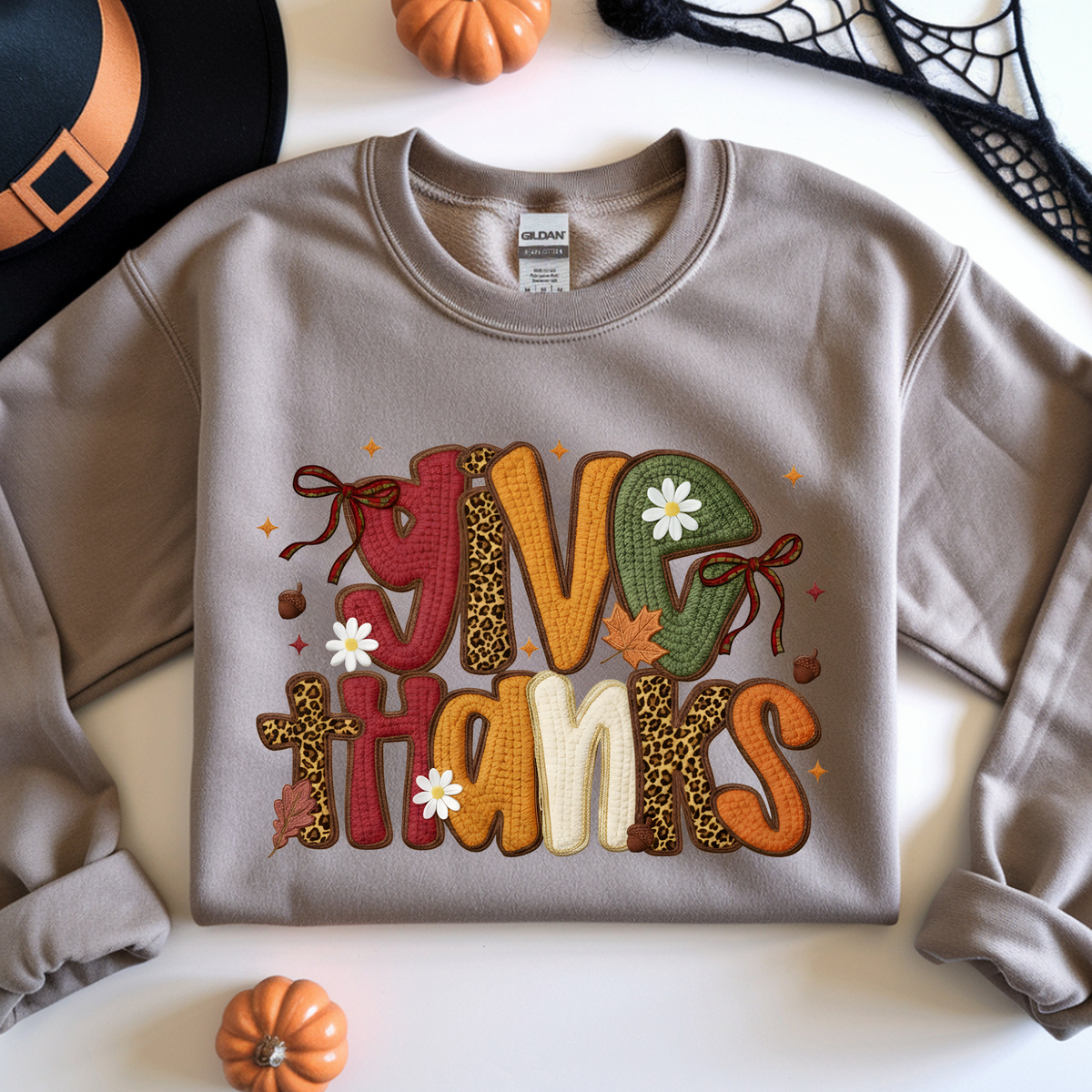 Large retro Give Thanks lettering decorated with colorful autumn patterns, pumpkins and fall leaves.