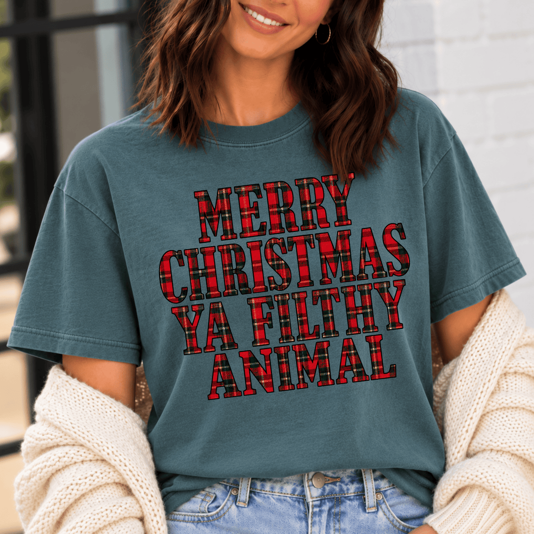 gray t-shirt featuring the phrase “Merry Christmas Ya Filthy Animal” in large, bold, red and black buffalo plaid lettering with black outlines, arranged in four stacked lines across the front.
