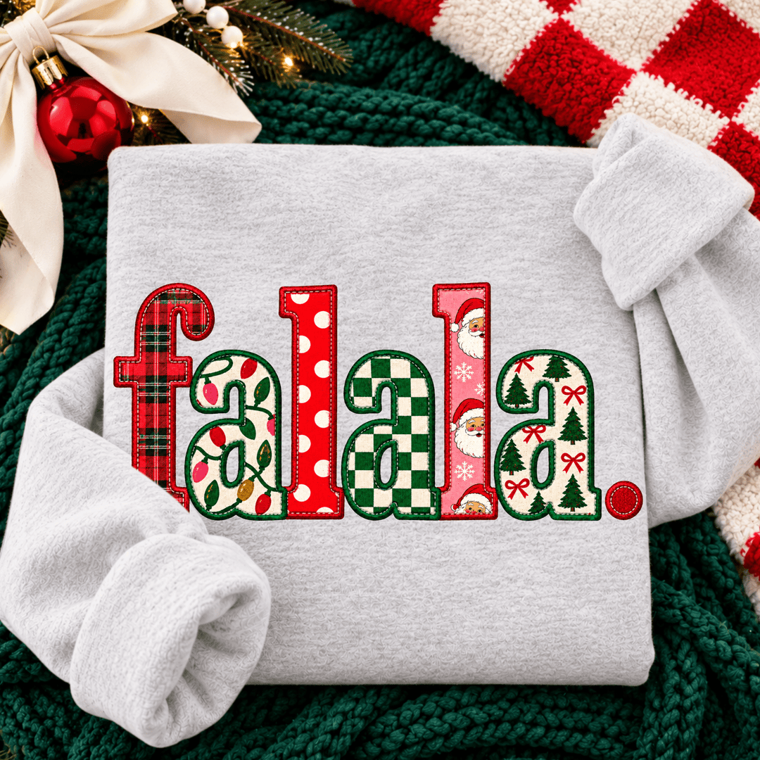 Christmas-themed “falala.” design featuring festive letters filled with red and green plaid, Christmas lights, polka dots, checkerboard, Santa faces, Christmas trees, and red bows on an ash gray sweatshirt.